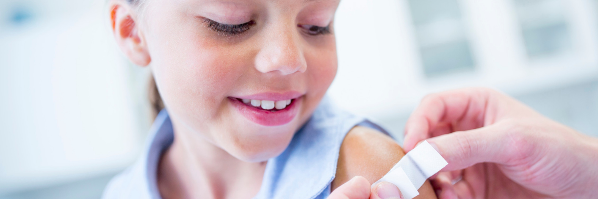 Doctor places bandage on smiling child's immunization site