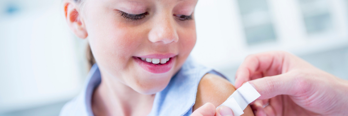 Immunization-Resources-Header Doctor places bandage on smiling child's immunization site