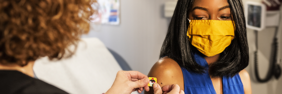 Doctor places a bandage on a woman's vaccination site