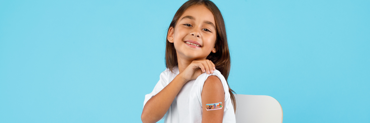 little girl shows off her vaccine bandage with a smile because vaccinations help protect the community